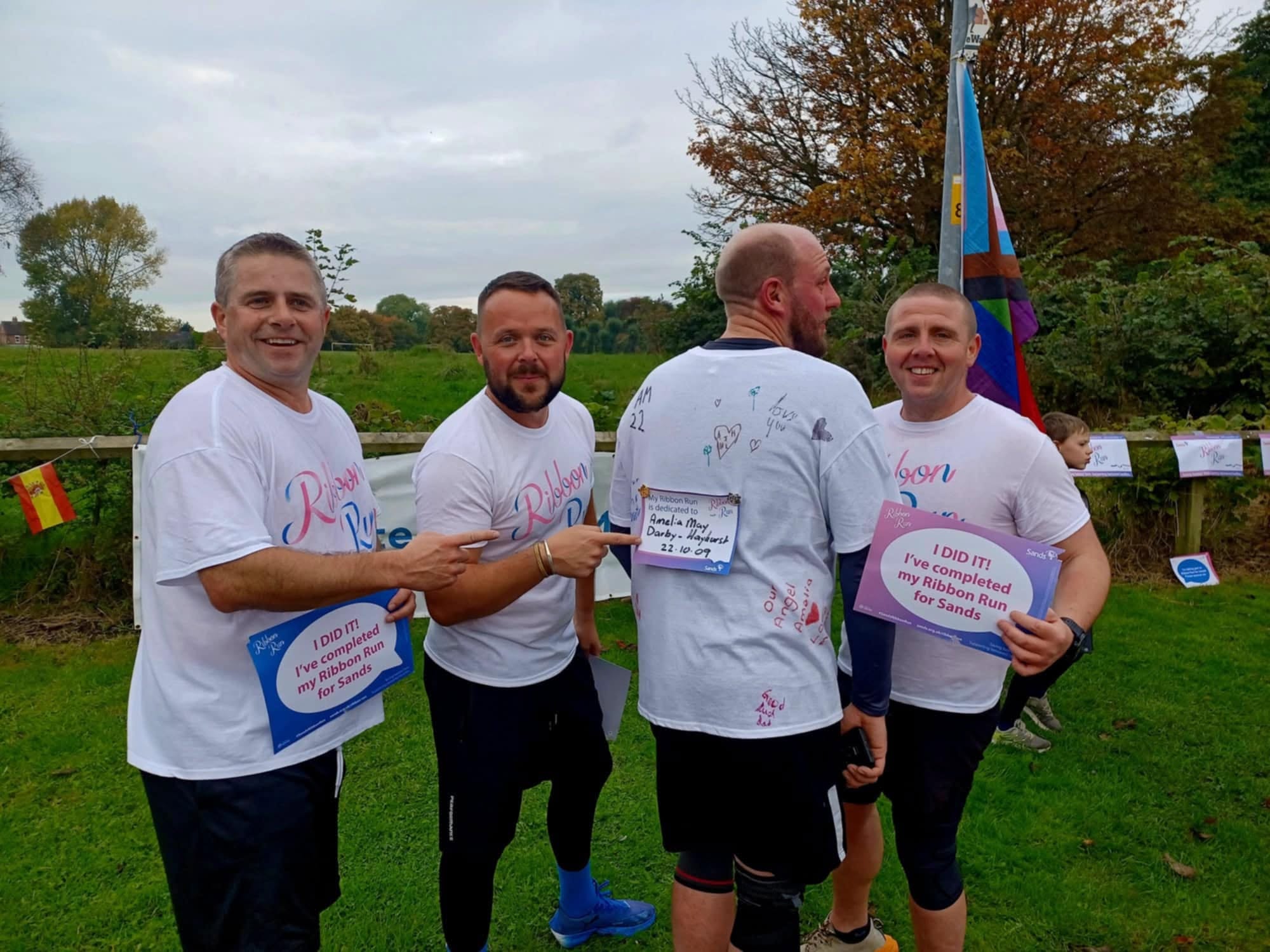 Four adults greeting one another in ribbon run shirts