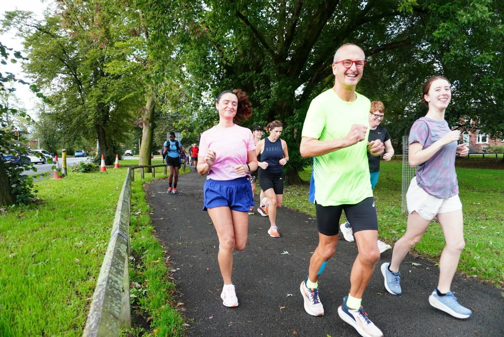 Three people running at their own pace on a path through the park