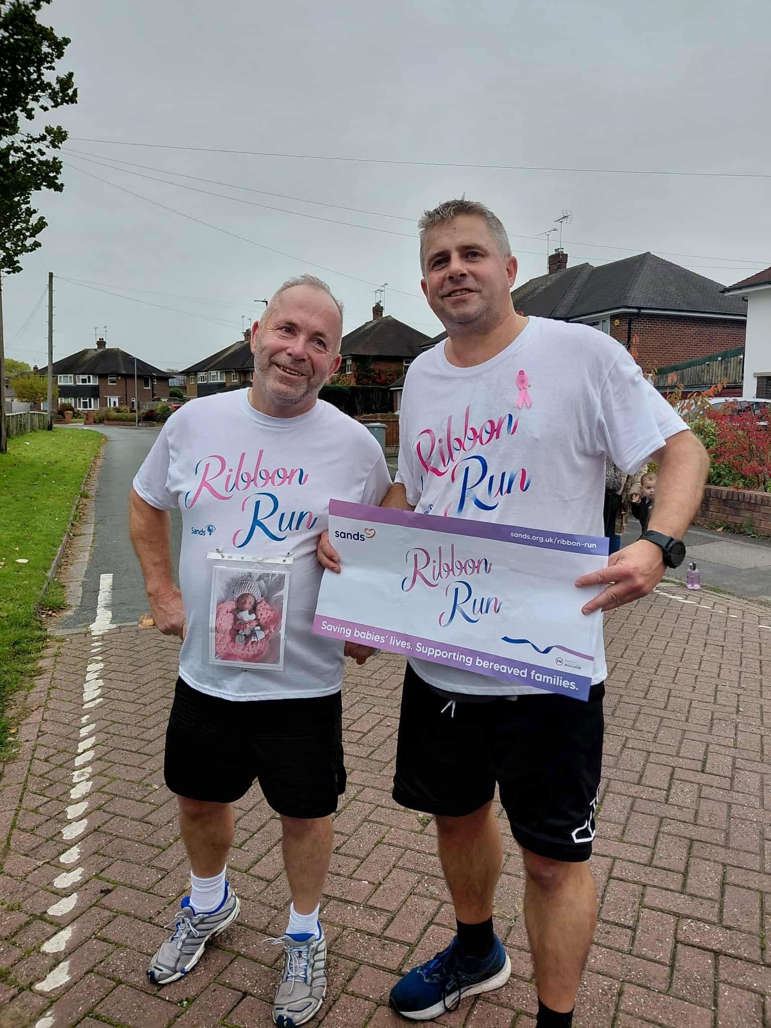 Two adults wearing ribbon run tops at a community gathering