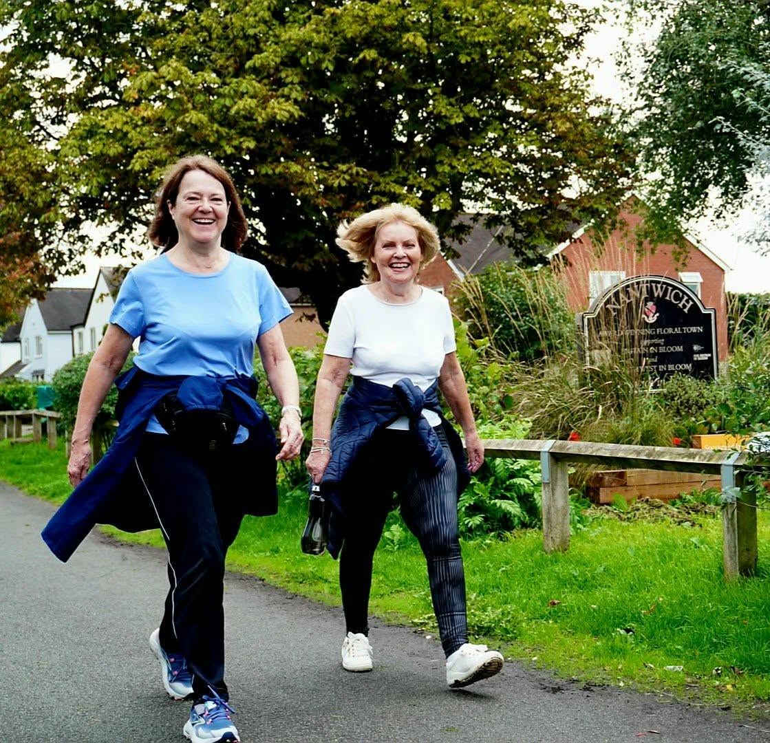 Two people walking together along a park path